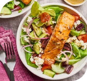 A bowl of fresh green salad topped with fish